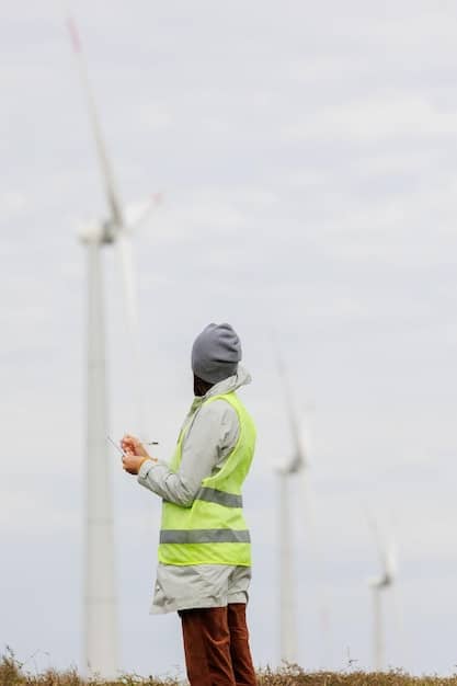A close-up shot of a wind turbine blade with a person in the background doing maintenance.