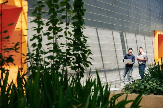 A shot of a modern, eco-friendly office building with large windows and greenery, showing people working inside. The image represents sustainable architecture and energy-efficient building design.