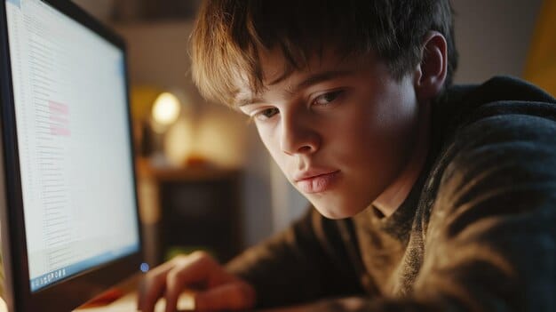 A close-up shot of a student working intently on a computer, with lines of code visible on the screen. The setting is a modern coding bootcamp, with multiple monitors and collaborative workspaces in the background.