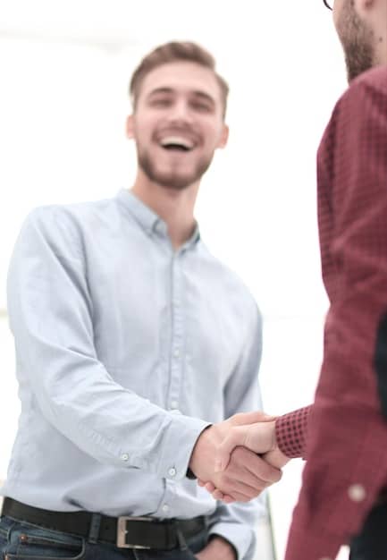 A close-up shot of two people shaking hands firmly after a successful negotiation. Both individuals are smiling, conveying trust and satisfaction.