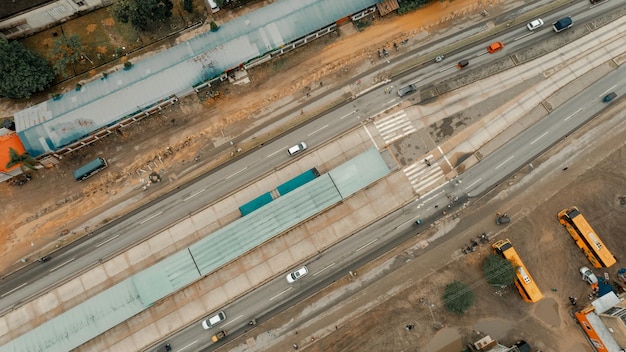 A close-up aerial photo of a highway interchange under construction. Heavy machinery is actively moving earth and laying asphalt. Workers in hard hats are visible, carefully overseeing the operation. The focus is on the complexity and scale of modern road infrastructure and its relation to 'Expert Analysis: The Impact of the Infrastructure Bill on Construction Companies'.
