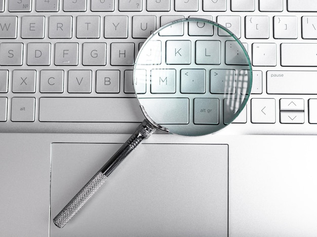 A conceptual image of a magnifying glass hovering over a computer screen displaying a search bar with 