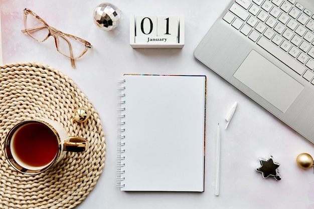 A detailed flat lay of a well-organized desk with a calendar open to January 2025, a planner, a laptop displaying a financial spreadsheet, and a cup of coffee, indicating financial planning and record-keeping.