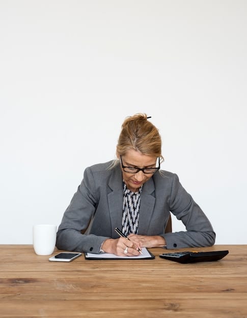 A person is reviewing documents at a desk with a calculator and a pen. The documents seem to be related to student loans and financial aid. The scene emphasizes the need for careful planning and understanding of the eligibility criteria of student loan forgiveness programs, as highlighted in 'Understanding Student Loan Forgiveness Programs: Are You Eligible for Up to $20,000 in Relief?'.