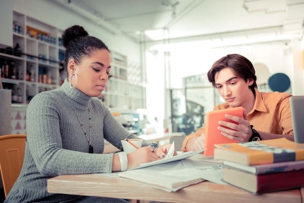 Two students sitting at a table in a library, working on college applications together. One student is pointing at a laptop screen, while the other is taking notes. The scene depicts the collaborative effort and research involved in navigating the college admissions process: expert advice on early decision vs. regular decision.