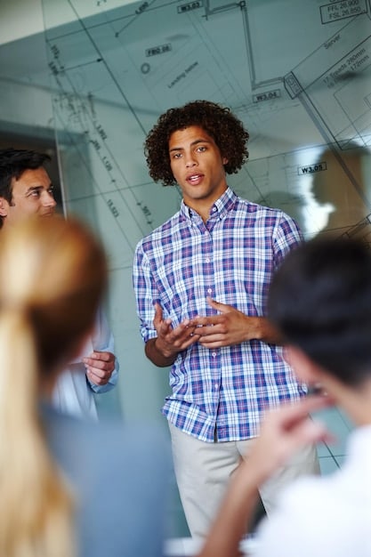 A close-up shot of a student intern presenting a project during a meeting, showcasing the professional skills gained in an internship. Other team members are looking on attentively, emphasizing the importance of communication and presentation skills. Relates to the power of internships: how to gain real-world experience and boost your resume before graduation.