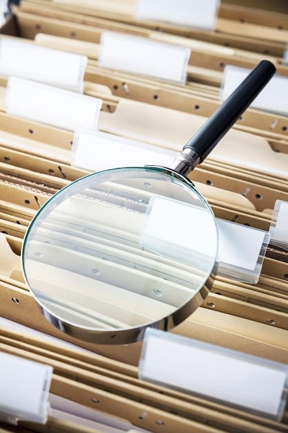 A close-up of official customs documents being reviewed with a magnifying glass, highlighting the meticulous nature of US Customs audits. Emphasizes accuracy and attention to detail in The Importer's Guide to US Customs Audits: Prepare Your Business for Success.